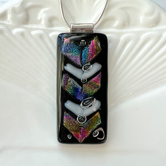 This geometric black dichroic glass necklace is a handmade necklace in colourful geometric shapes. This necklace has a base of opaque black with multicoloured dichroic and white chevrons. Dichroic glass is beautifully sparkly and has a lot of depth that is even more striking in real life.