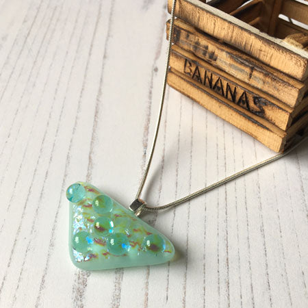 This aqua bubble dichroic glass necklace is a handmade necklace with aqua droplets on dichroic glass. The necklace has translucent aqua droplets on a translucent bed of shades of blue/purple dichroic glass.