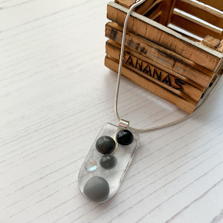 This dark monochrome bubble glass necklace is a handmade necklace with multicoloured droplets on a bed of clear glass.